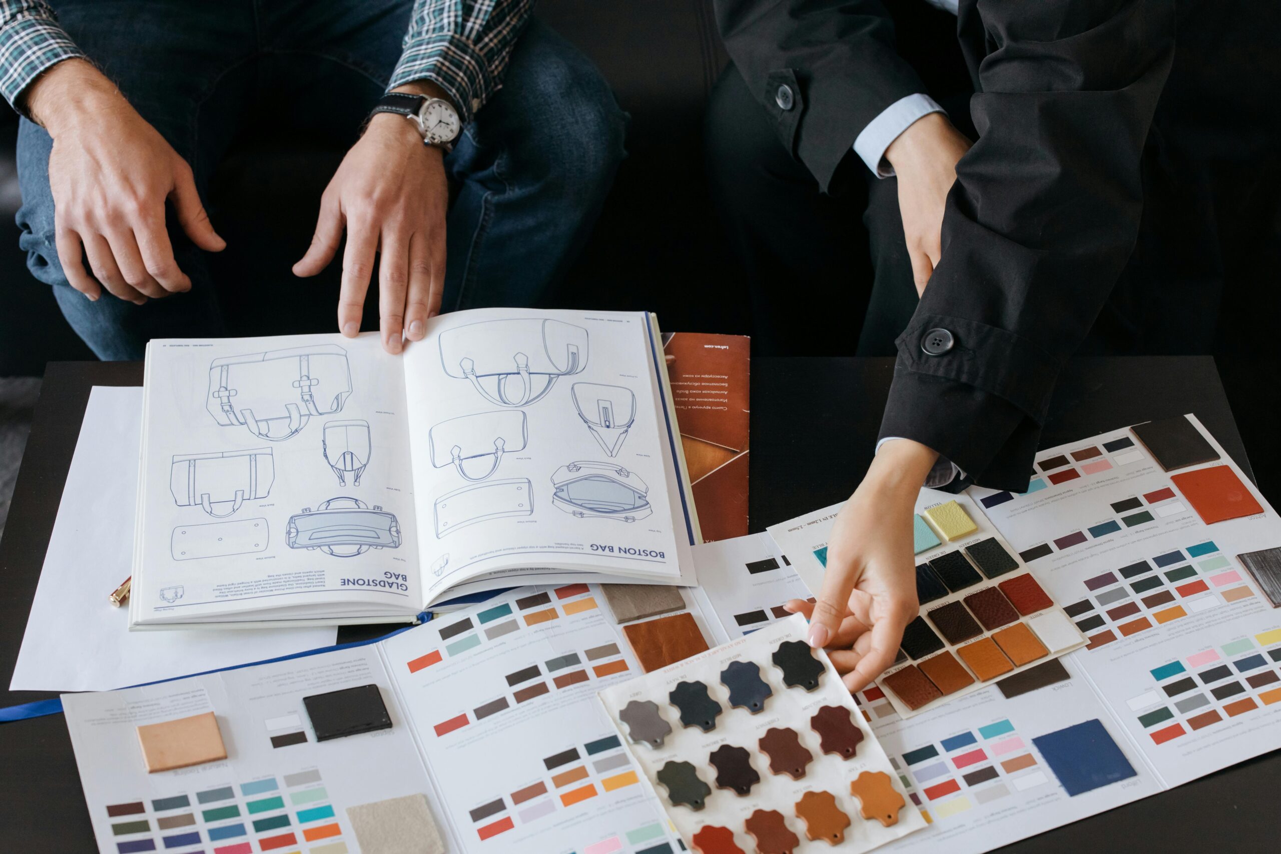 Two professionals choosing color swatches and bag designs for a fashion project.